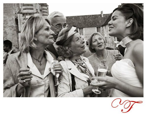 La mariée est sollicitée par les invités de son mariage devant le photographe du mariage