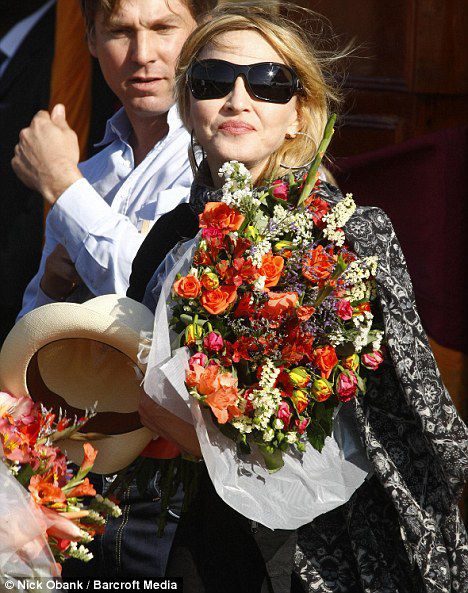 Holding a straw hat and bouquet of flowers, Madonna smiles as she arrives for the launch of the construction of her school in Malawi