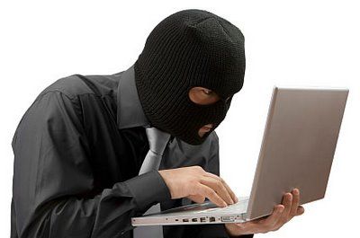 Homme cagoulé utilisant un ordinateur portable