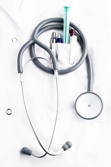 stethoscope, syringe and ballpoins on doctor's lab coat