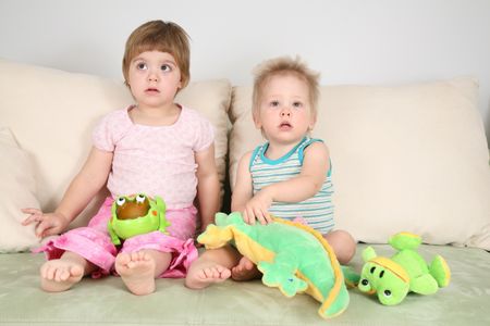 two children on sofa with toys