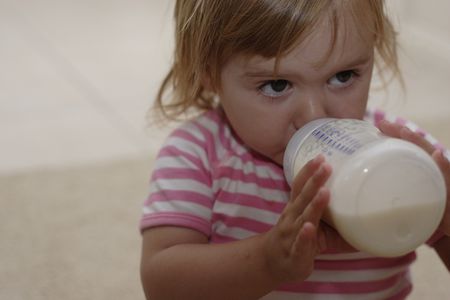 toddler holding and drinking milk