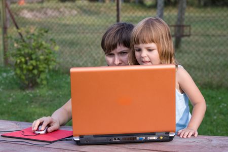 little girl playing computer game with adult woman