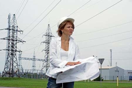 Woman engineer with safety hat drawings and electrical towers