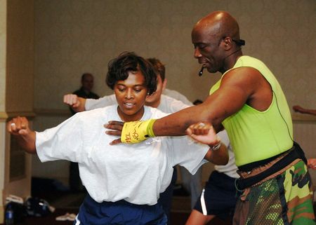 Fitness trainer Billy Blanks shows a female workout participant, the p