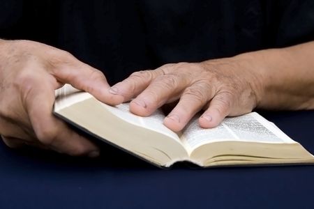 Old hands holding worn Bible