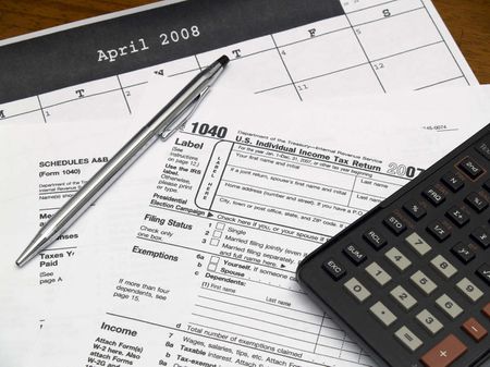 Income tax forms with a pen and calculator on a table.