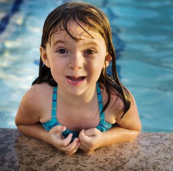 Little girl with pretty smile playing in swimming pool