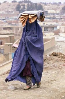A woman wearing burqa in Afghanistan, carrying freshly baked Afghan br