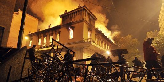 En février 2012 à Athénes, après que le Parlement grec eut adopté un nouveau plan d'austérité - Photo http://s2.lemde.fr/image/2012/02/12/534x267/1642391_3_aeed_un-incendie-detruit-un-magasin-durant-les_256ae480c4b00971d1a7d0cfbdd2fc47.jpg - Un an plus tard, qu'est denenue la Grèce ? 